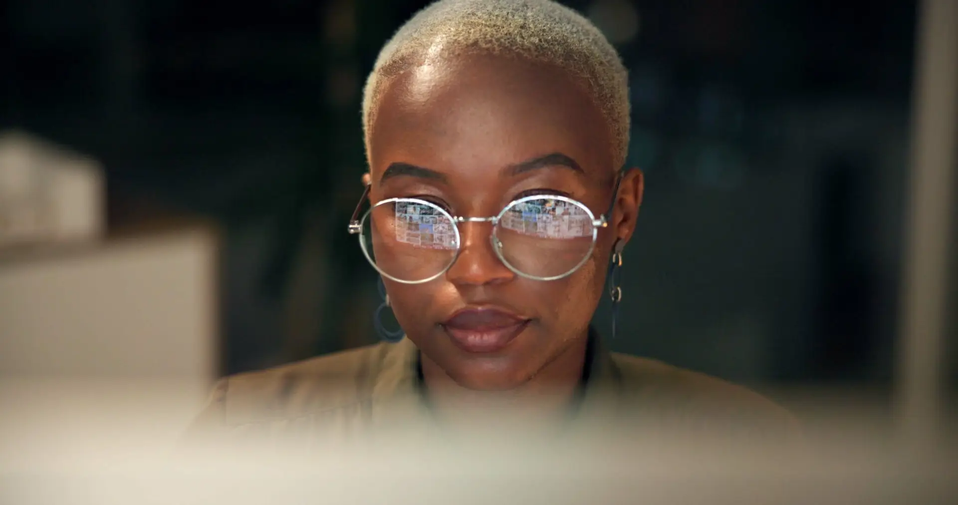 Black woman, glasses and computer in office for news, business research and reflection at night. Economy journalist, tech or reading in agency for article resource, proofreading or stock market study.