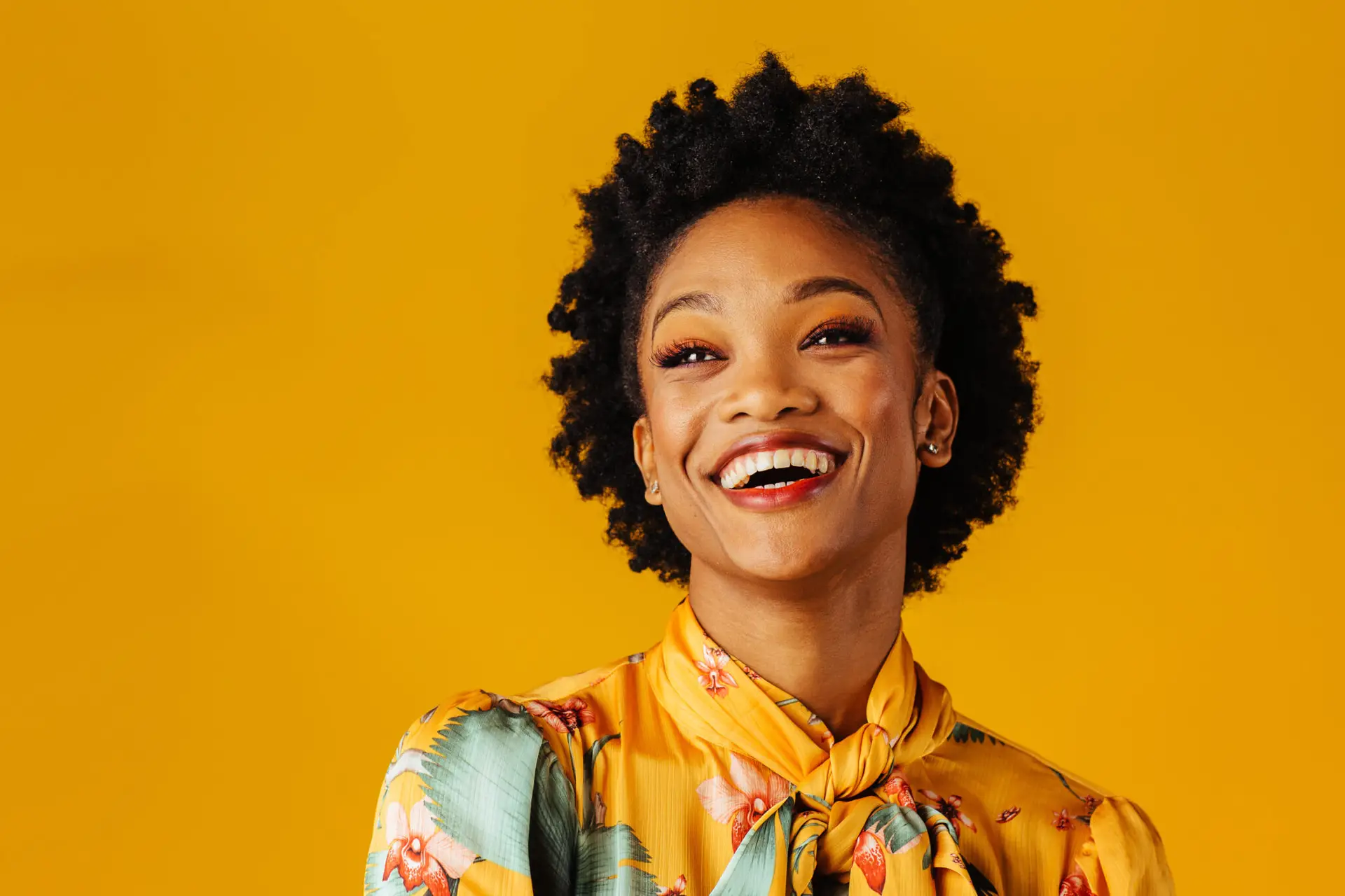Portrait of a very happy and excited young woman smiling and looking up in an elegant floral top