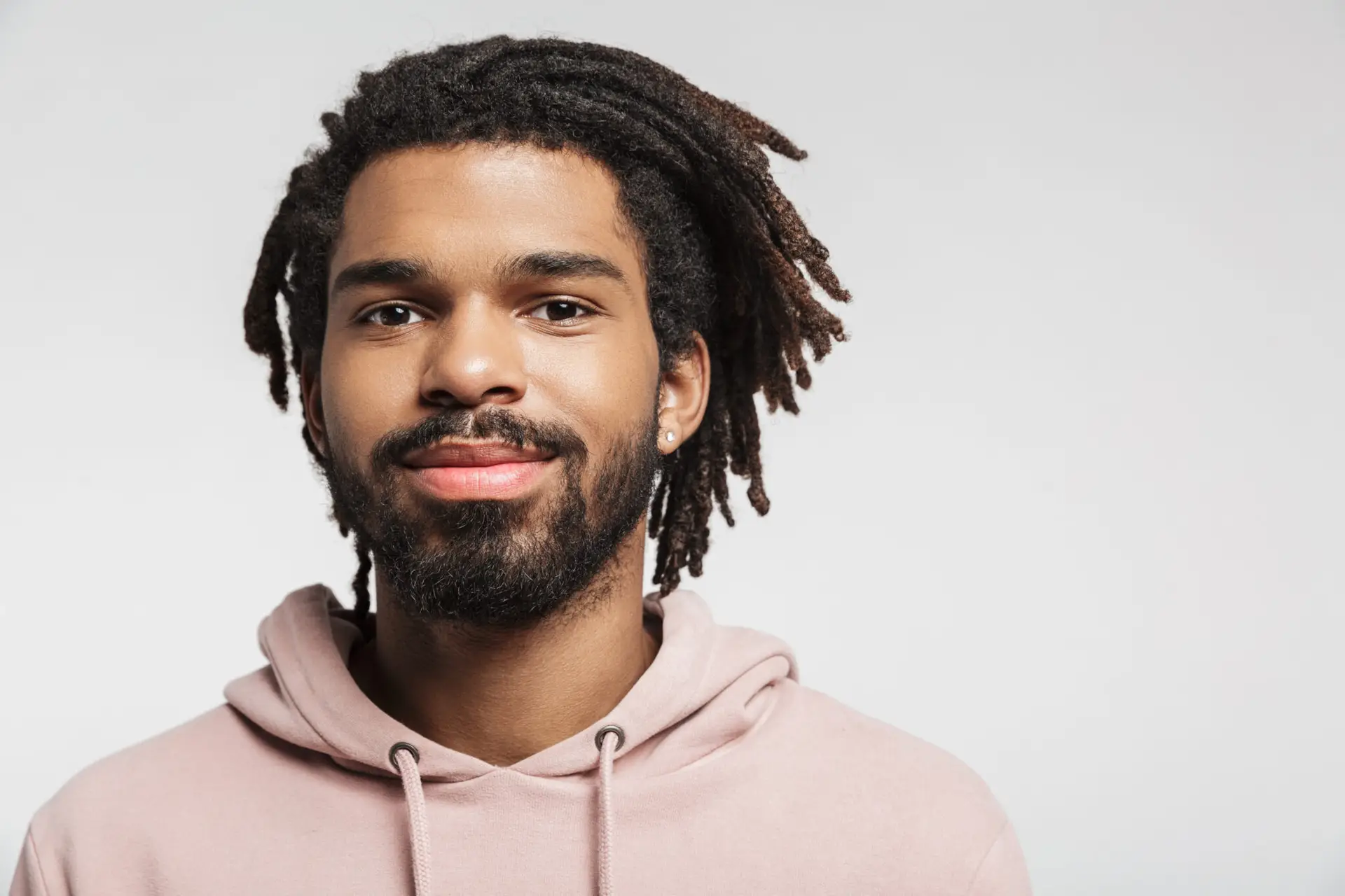 Close up portrait of a smiling young african man wearing hoodie standing isolated over white background, looking at camera